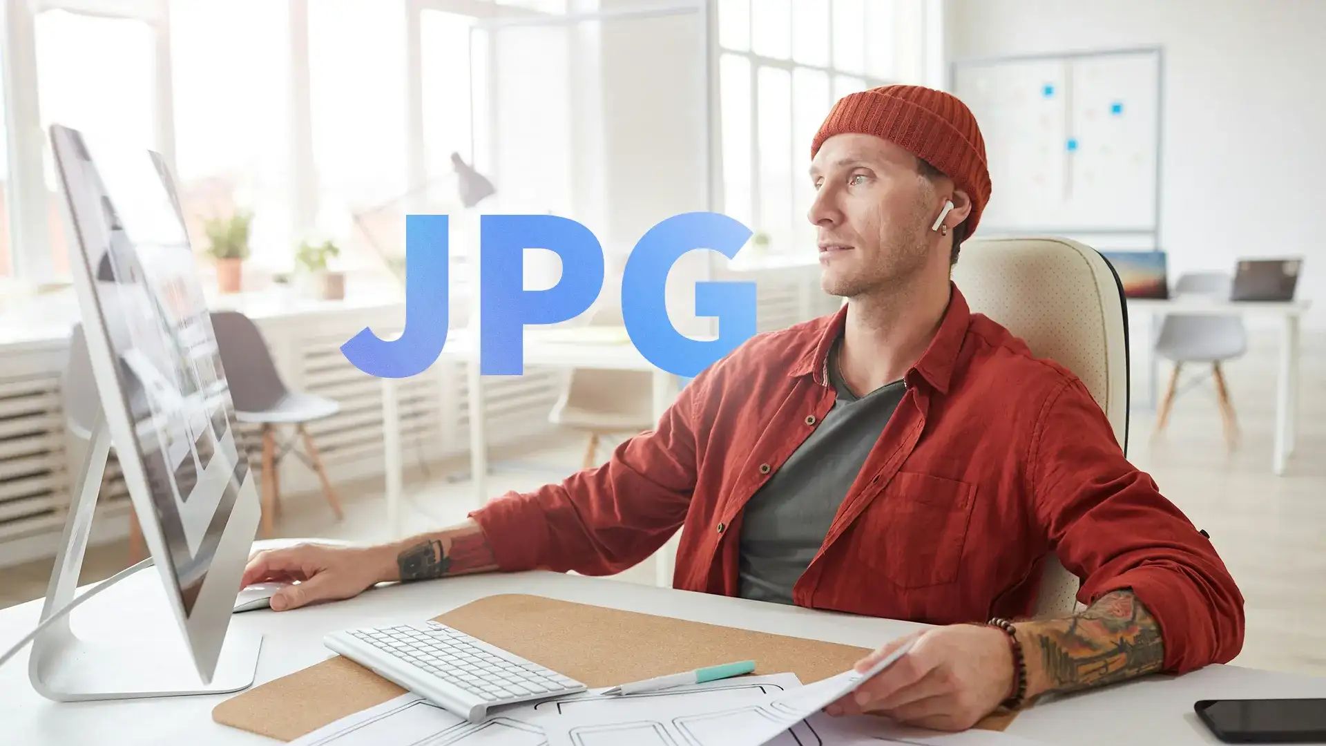 Man at a desktop computer in a bright office with the letters JPG across the frame