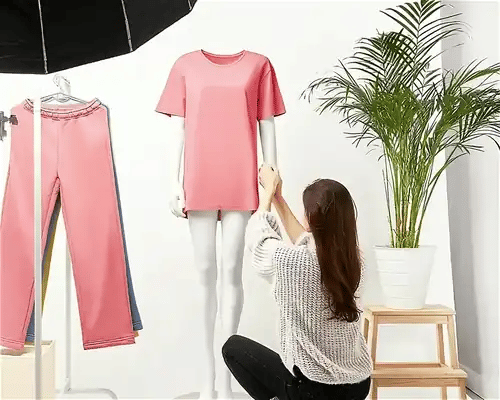 Sesja zdjęciowa odzieży - stylistka przygotowuje różowy komplet na manekinie w studiu fotograficznym