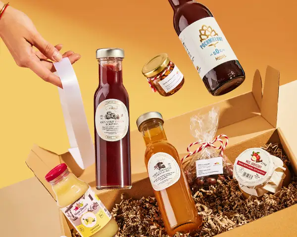 Zestaw prezentowy produktów spożywczych w kartonowym pudełku z słoikami, butelkami i miodem na pomarańczowym tle