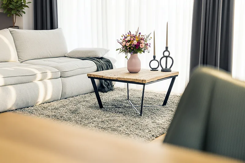 Elegancki salon z bukietem kwiatów w wazonie na drewnianym stoliku kawowym i szarą sofą